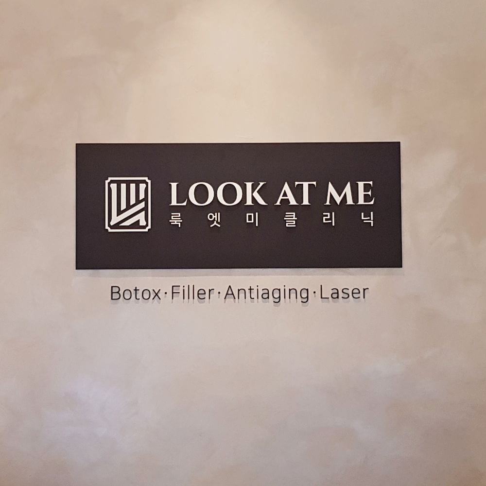 석회 미장 벽에 걸린 LOOK AT ME 룩엣미클리닉 로고판